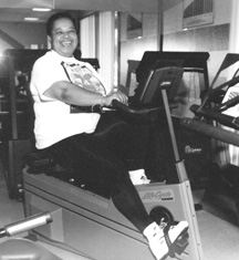 Photo of a woman smiling while peddling an exercise bike